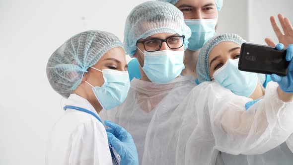 Team of Doctors During Coronavirus Pandemic Hold Videoconference with Colleagues By Phone alt