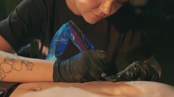 Female Tattoo Artists Work with Bare Client Chest Fills Ink with Needle Machine