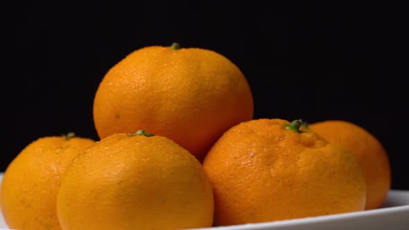close-up of tangerines spinning on a turntable on a plate on a black background alt