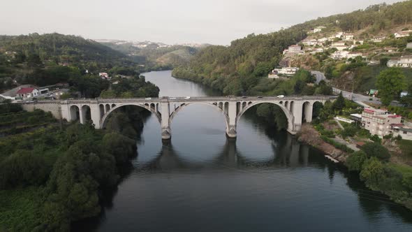 Panoramic aerial circling drone view of famous Ponte De Pedra Bridge over Douro river, Entre os Rios