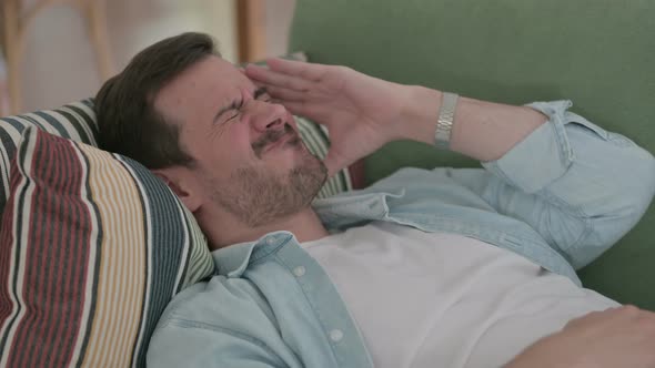 Close Up of Young Man Having Headache While Lying on Sofa alt