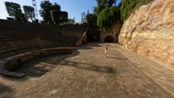 Drone Shot of a Girl in a White Tight Suit Staying in the Ancient Amphitheater alt