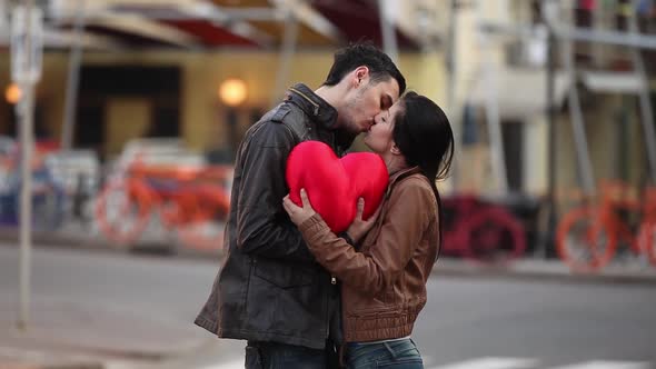 young couple with a heart hugging in the street