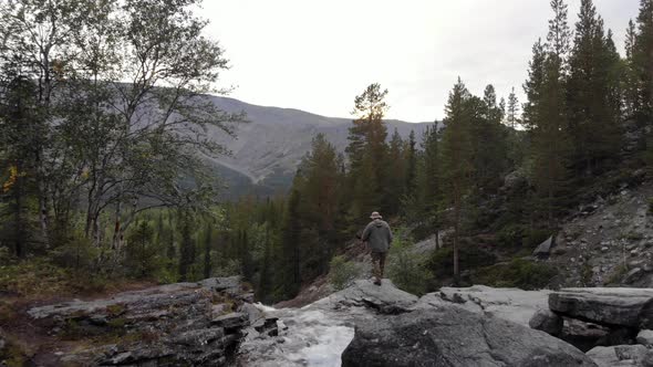 Active Traveler Jumping From Stone to Stone on the Surface of a Mountain River alt
