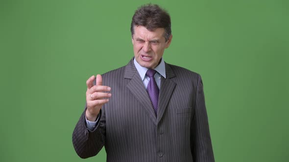 Mature Handsome Businessman Against Green Background alt