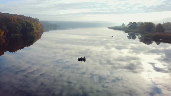Two men are fishing in a boat on the river. autumn landscape. Aerial view.