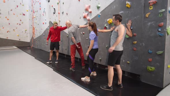Four People Stretching near Climbing Wall alt