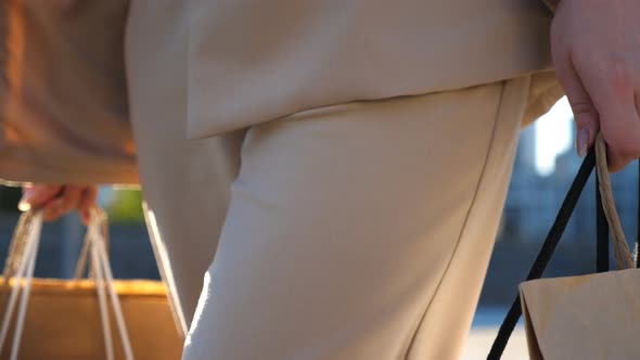 Hands of Young Woman Carry Shopping Bags Walking Along Urban Street alt