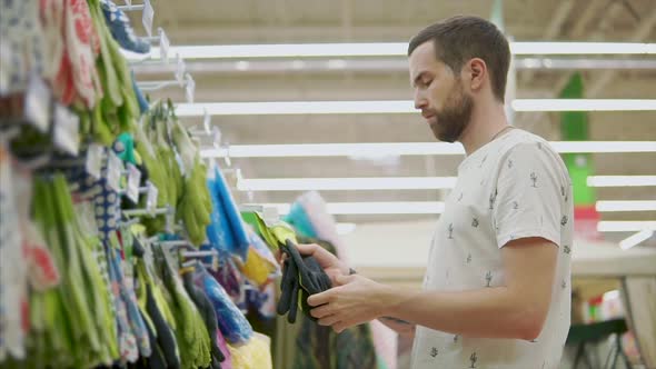 Male Shopper is Feeling Protective Rubber Gloves in Hands in Hypermarket alt