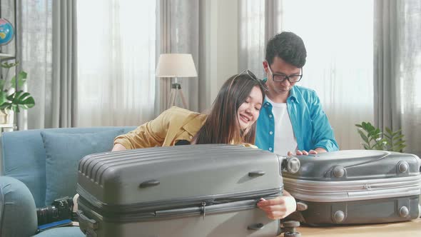 Happy Asian Couple Travelers Close Suitcase For A New Journey. Luggage For Travel Holidays alt