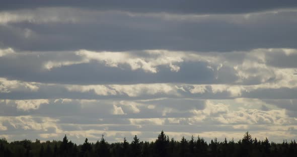 Fast moving clouds over the forest horizon silhouette time lapse