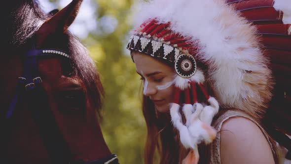 Woman In Headdress Head To Head With Horse In Forest alt