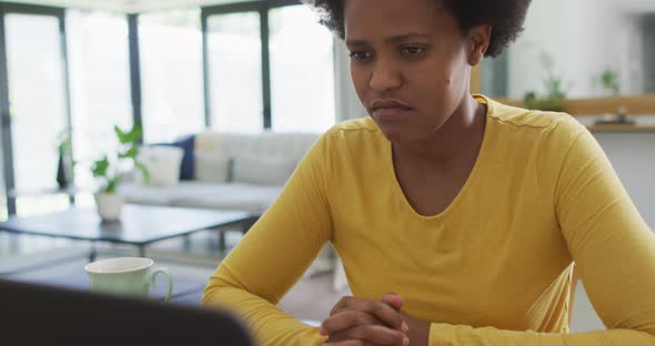 Tired african american woman sitting at table using laptop, Stock Footage