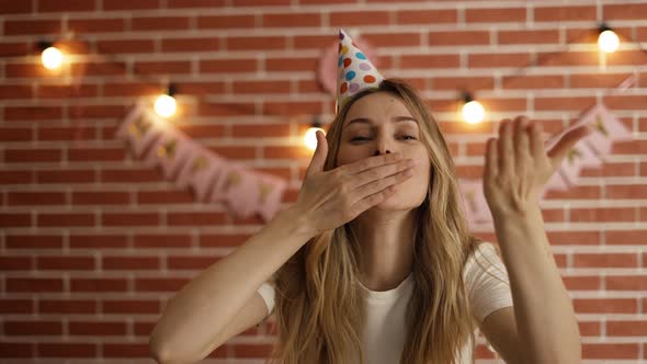 Portrait of Woman Celebrating Birthday Looking at Camera Positively and Blowing Air Kiss alt