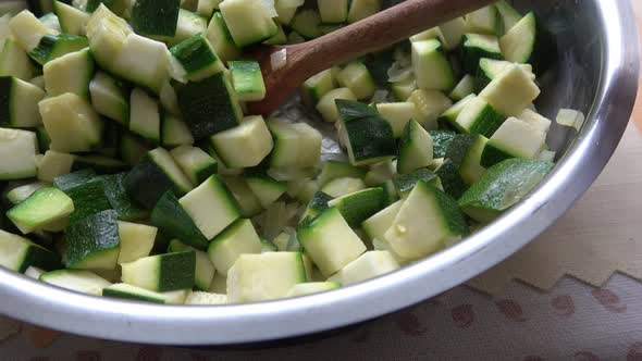 Vegetables cut in cubes fried on frying pan, in kitchen.