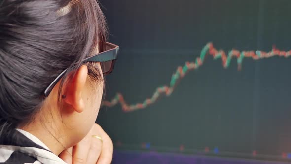 Young businesswoman working in office with red and green candlestick chart and stock. alt