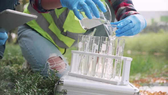Close up of Scientist woman collecting samples of factory wastewater in a test tube