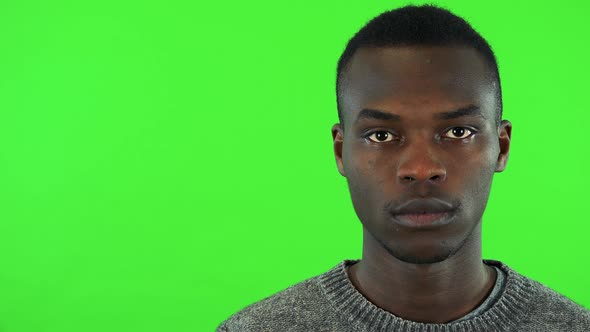A Young Black Man Looks at the Camera - Face Closeup - Green Screen Studio