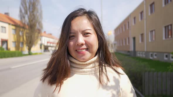 Close up outdoor portrait of a happy Asian woman with long straight hair and smile face alt