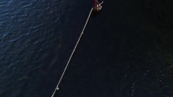 In the Middle of a Flooded Field in a Flood on a Wooden Crossbar Sits a Man with a Guitar