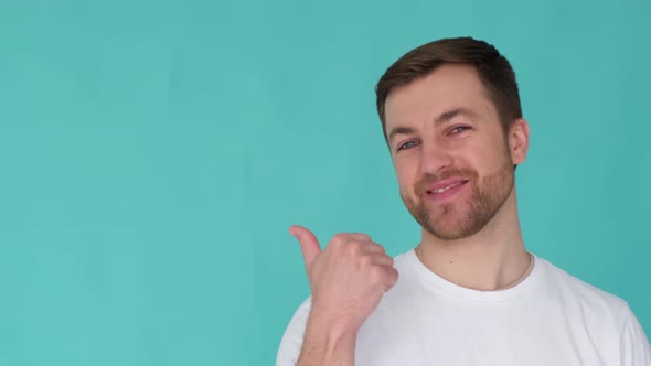 Handsome Male Guy Pointing His Thumb at Empty Space for Copy Isolated Background in Studio alt