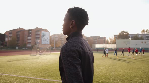 A Cheerful Young African American Woman Goes on the Treadmill of the City Stadium and Smiles alt