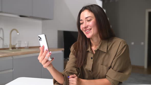 Pleased Young Asian Woman Has Video Call on the Smartphone