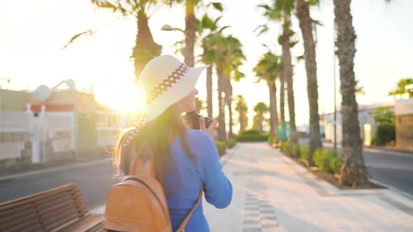 Photographer Tourist Woman Taking Photos with Camera in a Beautiful Tropical Landscape at Sunset alt