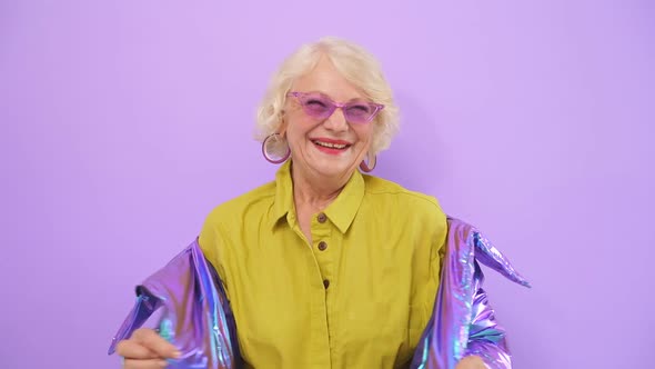 Smiling Cheerful Old Lady Posing for the Camera, Isolated Purple Background alt
