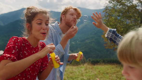 Family Enjoy Blowing Soap Bubbles for Children Closeup alt