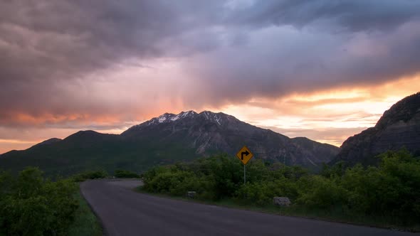 Sunrise time lapse looking at mountain and colorful clouds down road alt