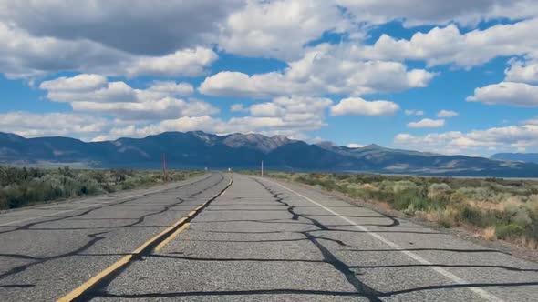 Small Asphalt Road Surrounded By Desert with Clouded Blue Sky. alt