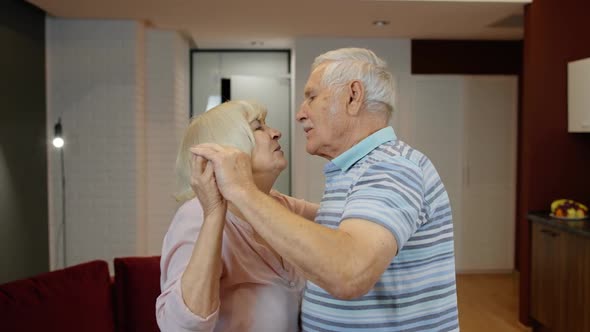 Happy Carefree Elderly Senior Grandparents in Love Dancing Waltz in Modern Living Room at Home alt