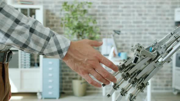 Close-up Shot of Man and Intelligent Robot Shaking Hands in Office Room alt