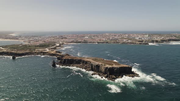 Aerial orbiting view Rocky Papoa islet revealing Peniche village Peninsula. Portugal