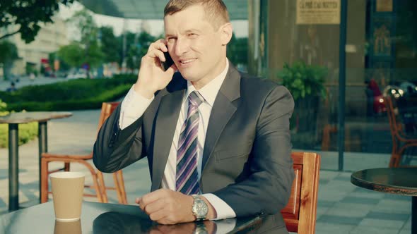 A Middleaged Businessman in Luxurious Clothes Answers the Call of His Mobile Phone the Business Man alt