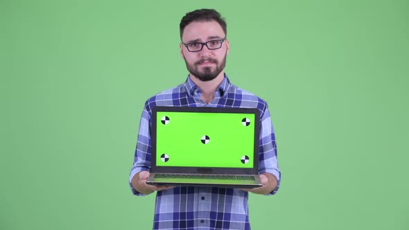 Stressed Young Bearded Hipster Man Showing Laptop alt