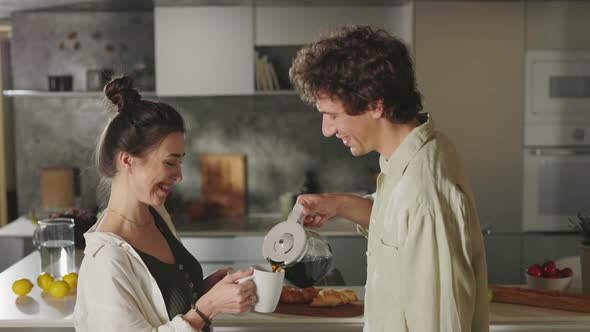 Couple Standing on Kitchen Talking and Drinking Coffee alt