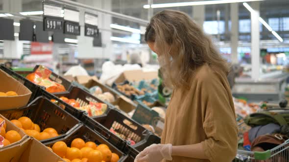 Woman in a Medical Mask and Gloves Selects Oranges in a Grocery Supermarket. Protection From the alt