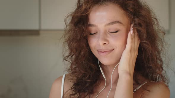 A Young Woman is Listening to Music and Smiling alt
