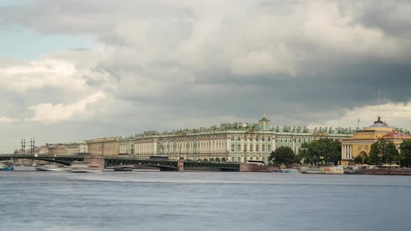 Dramatic cloudy sky over the Bridge and Winter Palace with boats on the Neva River alt