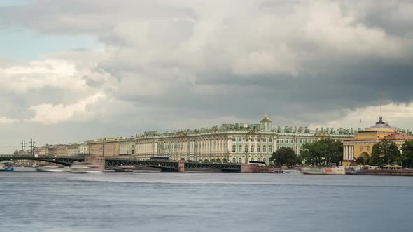 Dramatic cloudy sky over the Bridge and Winter Palace with boats on the Neva River