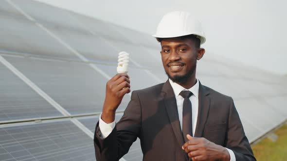 Portrait of African American Man in White Hardhat and Black Suit Smiling on alt