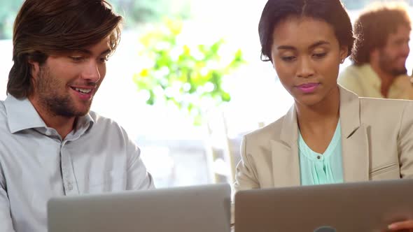 Businesspeople using laptop during meeting alt