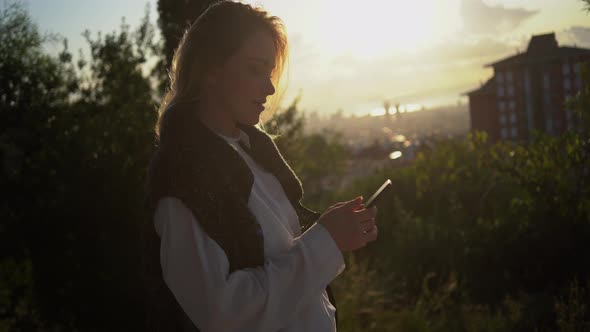 Woman with smartphone walking and writing text message alt
