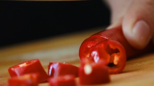 Knife Cutting Red Chilli Pepper on Wood