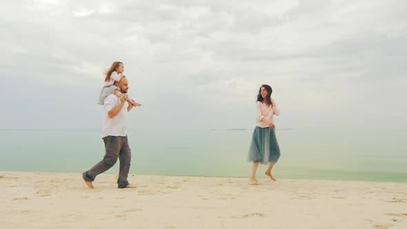 Happy Family of Three People Running on the Beach. Fun Games with Children alt
