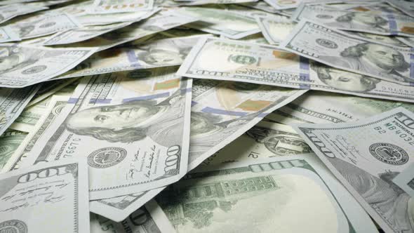 Moving over top of pile of 100 dollar bills on table alt