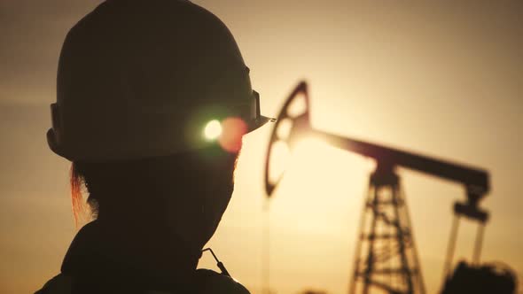 Silhouette Woman Engineer Wearing White Helmet and Work Clothes at Sunset. Industrial, Oil and Gas alt
