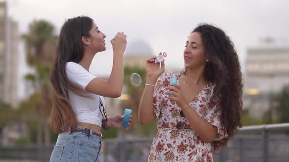 Happy Hipster Teenage Girls Blowing Bubbles in City Slow Motion